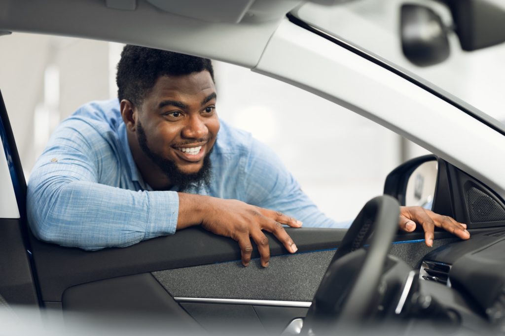Man Buying Car Looking At Vehicle Interior In Dealership Center